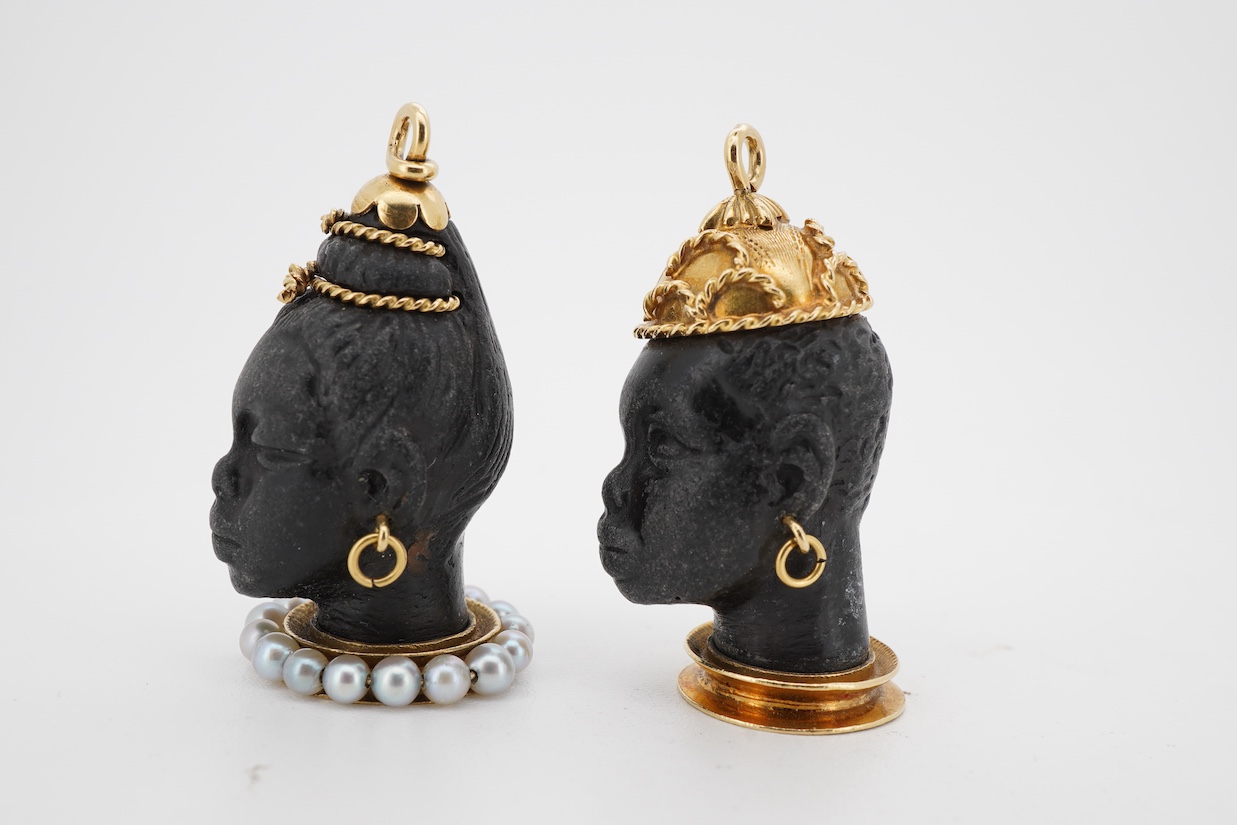 Two yellow metal mounted carved Blackamoor head charms, one with seed pearl set base, both overall approximately 30mm.